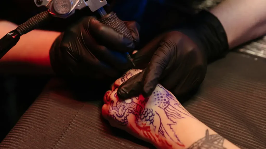 Tattoo artist using NovaTekDeals 5 Mil black nitrile gloves bulk for precision work